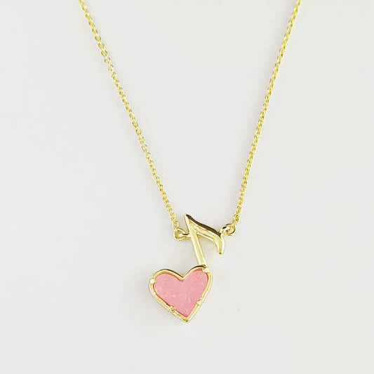 Gold-tone pendant necklace with pink heart and music note drop on chain