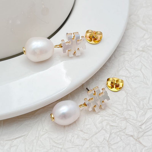 White pearl drop earrings laid out: white shell accents with gold posts