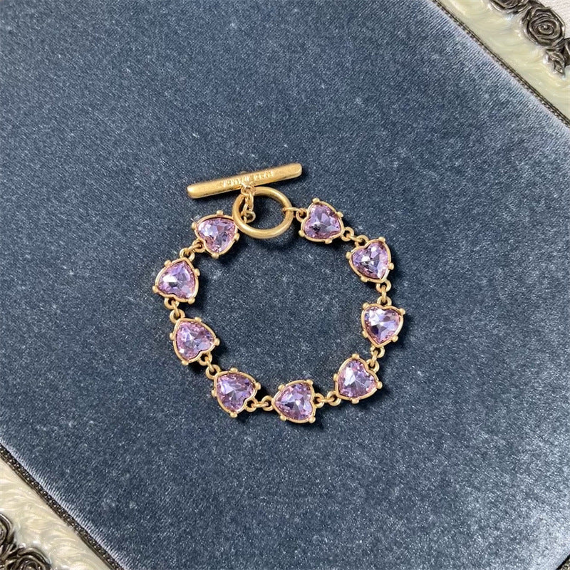 Gold-tone heart crystal bracelet with purple faceted heart stones and toggle clasp
