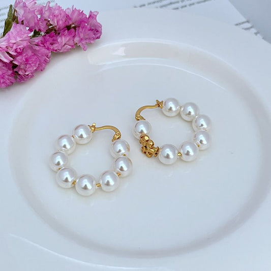 Pair of gold-tone hoop earrings with round white pearl beads and charm detail