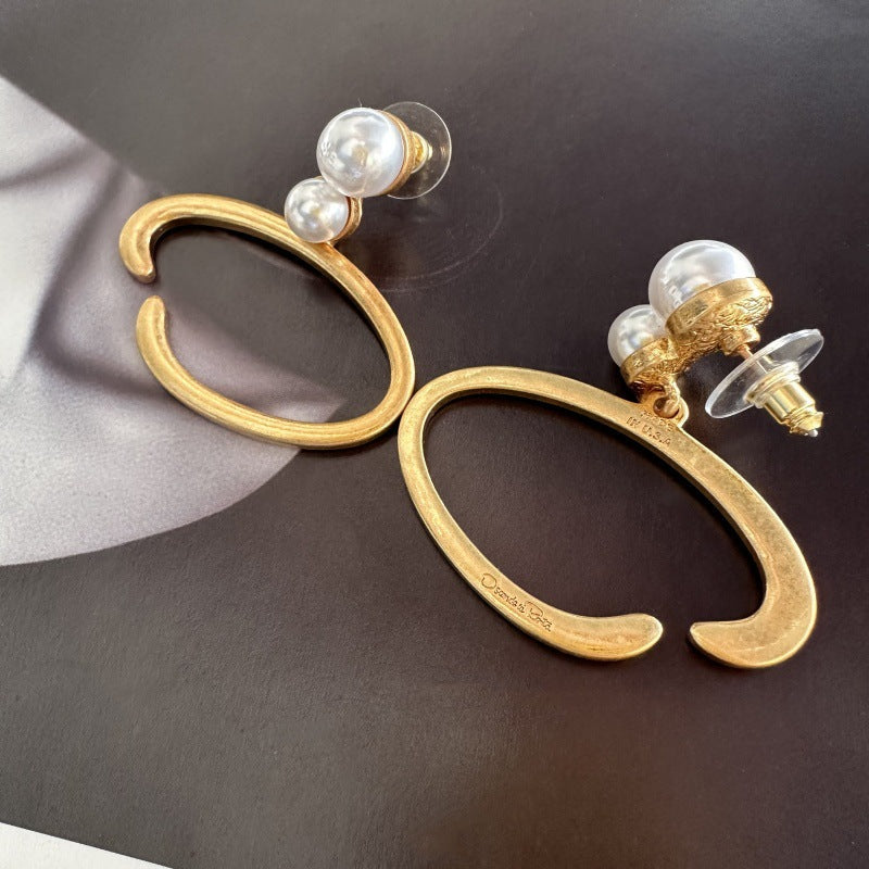 Gold-tone O-ring pearl earrings with visible post backs and white pearl drops