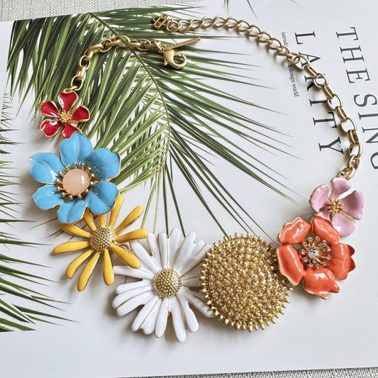 Gold-tone enamel flower necklace with blue, yellow, white, coral, and red daisy charms