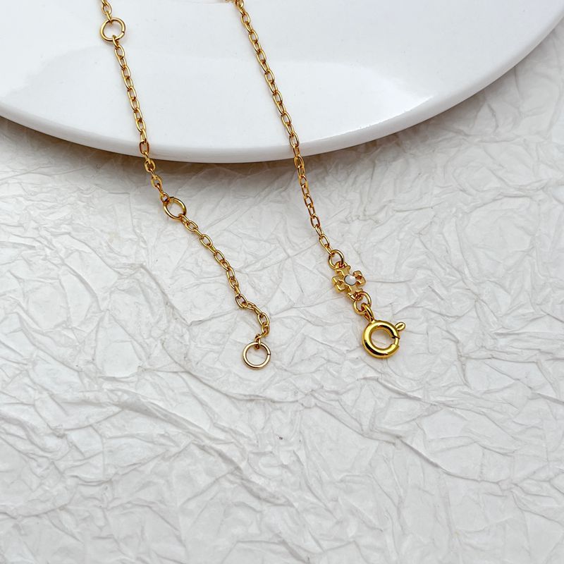 Gold-tone necklace chain with lobster clasp, ring links, and small clover detail