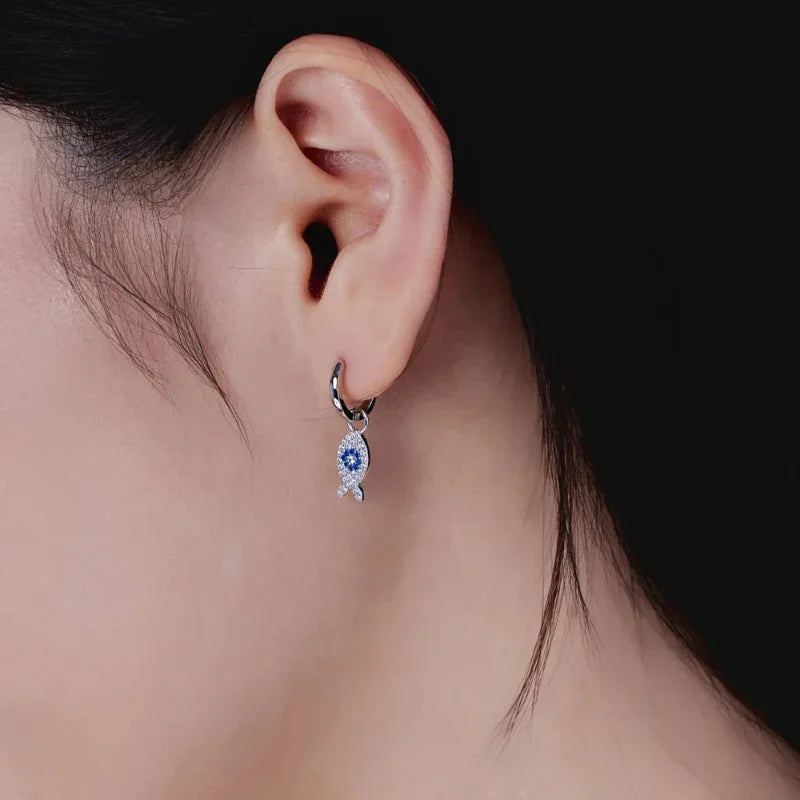 Silver fish dangle hoop earrings with blue zirconia center and clear stones, close-up