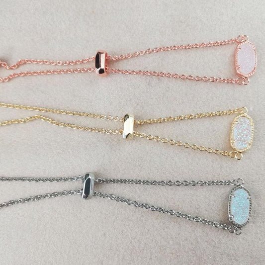 Adjustable chain bracelets with oval stone charms and metal slider clasps, pink, gold, and silver.