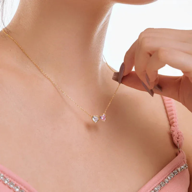 Gold-tone double heart pendant necklace with clear and pink CZ heart stones close-up