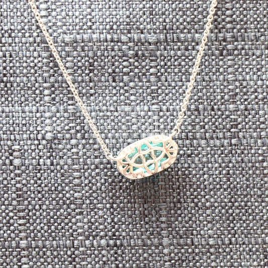 Pendant necklace with oval filigree charm and teal-blue inlay, on fine chain