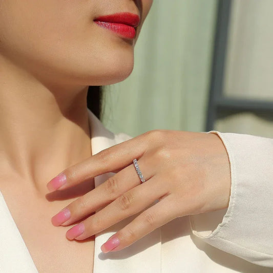Moissanite ring on finger with slim white-gold band and round prong-set stones