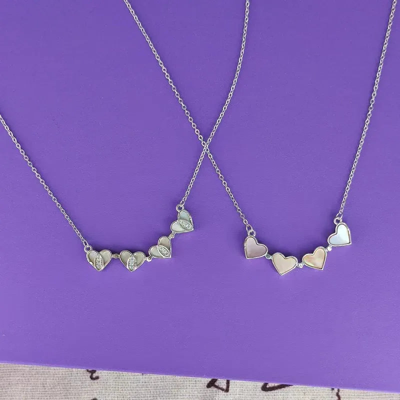 Heart charm pendant necklace set with heart-shaped charms on thin link chains.