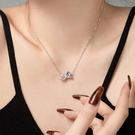 Silver CZ bow pendant necklace with light blue heart stone on a chain