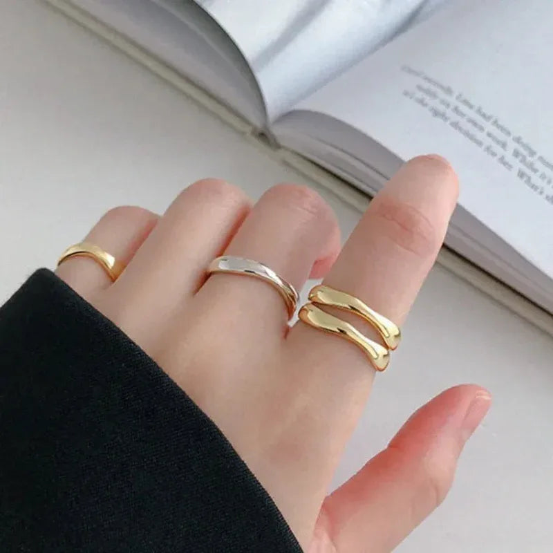 Gold wave ring and silver wave ring on fingers, smooth curved bands