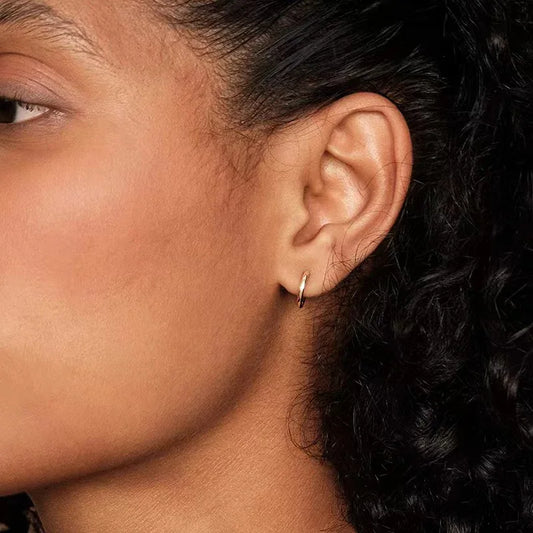 Gold hoop earrings with hinged closure, small round hoop on ear