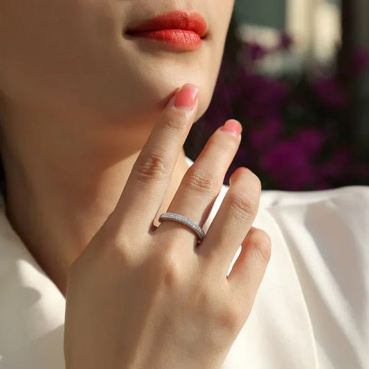 Moissanite wedding ring on a woman’s finger, silver band with small round stones