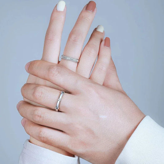 Silver couple rings on a hand: stone-studded band and smooth band with a small round stone