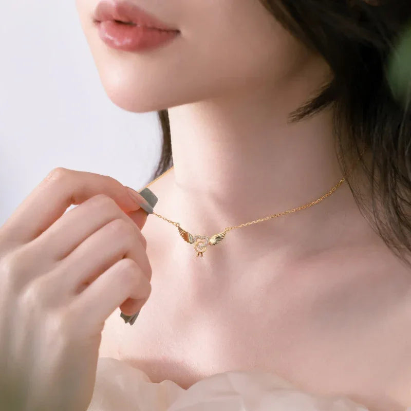 Gold-tone heart and angel wings CZ pendant necklace worn by a model