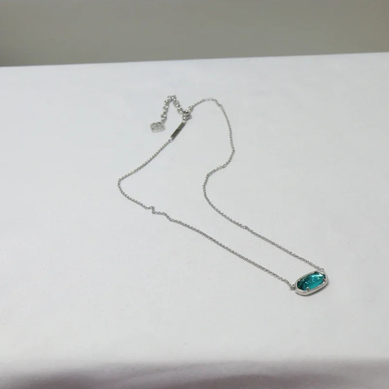 Silver-tone pendant necklace with small top charm and teal oval stone drop