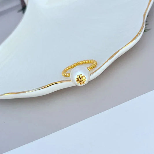 Gold-tone beaded ring with white pearl center and curved profile view