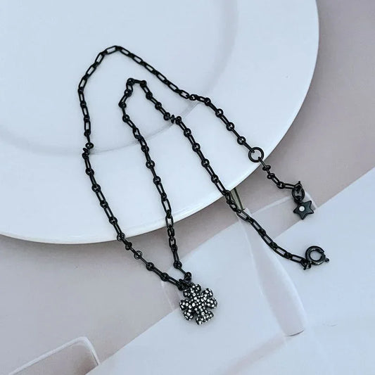Black chain bracelet with dangling rhinestone clover charm and star clasp detail