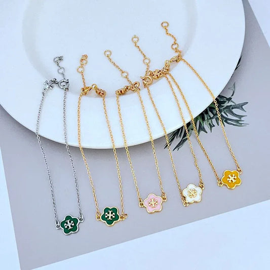 Set of four flower charm bracelets in gold and silver tones with enamel details