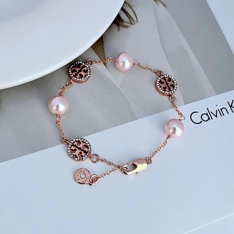 Rose gold pearl bracelet with round logo charms, pink beads, and lobster clasp