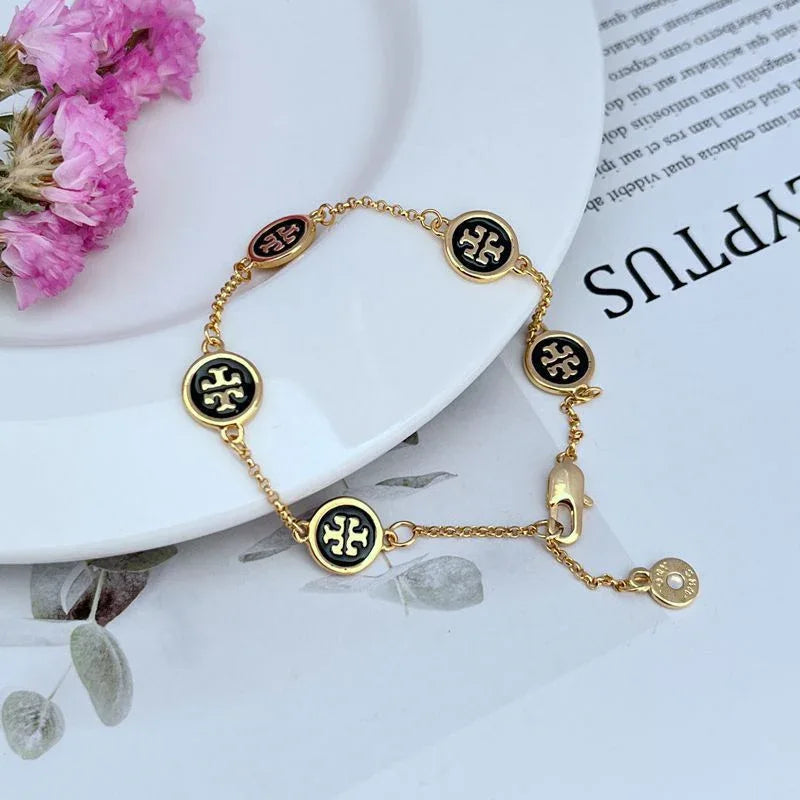 Geometric round enamel bracelet with black and red gold medallions and extension clasp.
