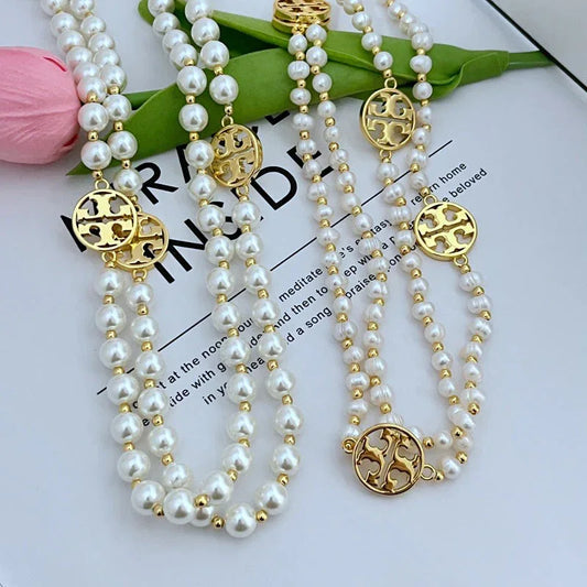 Pearl sweater necklace with multiple strands of white pearls and round gold-tone medallion charms
