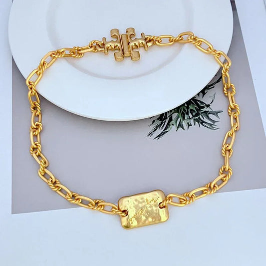 Gold-tone chunky chain bracelet with rectangular tag centerpiece and Tory Burch logo detail.