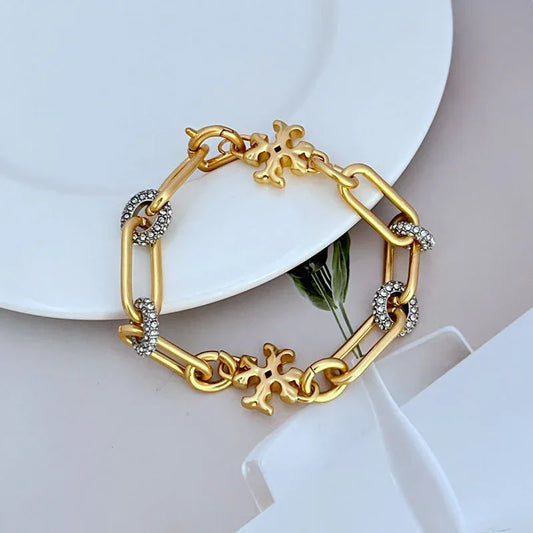 Gold-tone link bracelet with round crystal encrusted links and clover charms