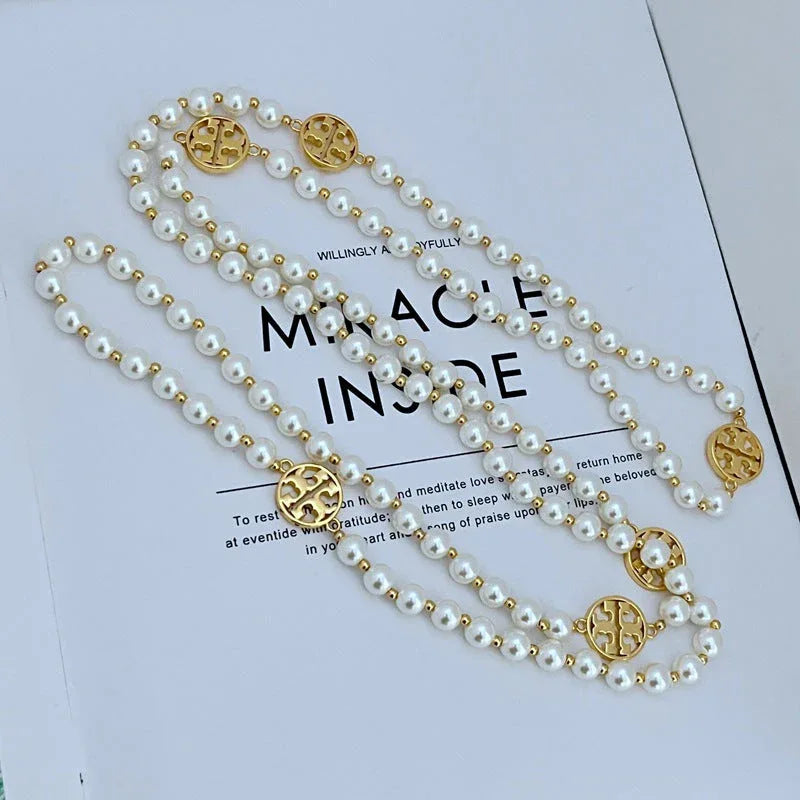 Pearl sweater necklace with three white pearl strands and gold-tone round medallion charms