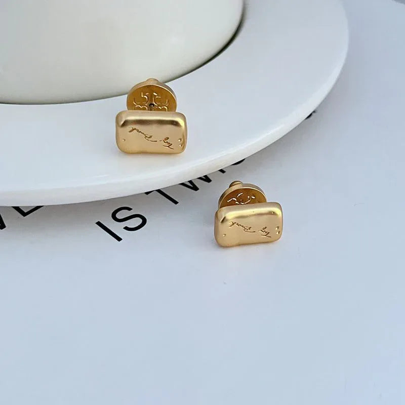 Goldfarbene Ohrstecker mit quadratischer Reliefplatte und kleiner runder Rückseite