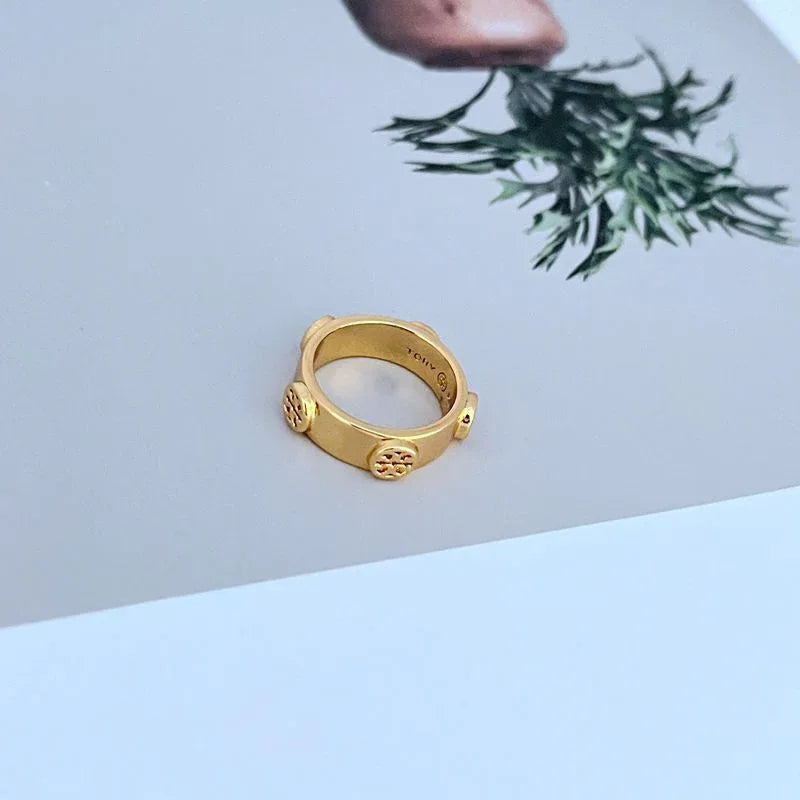 Gold metal ring with engraved logo on inner band and scalloped side posts
