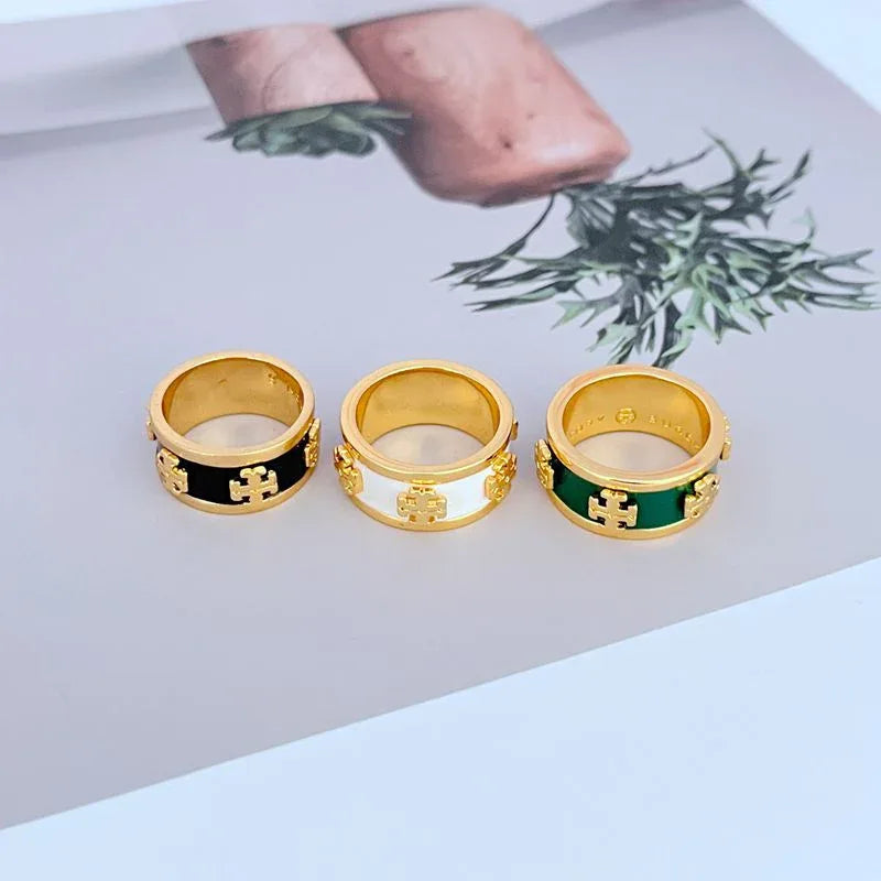 Wide enamel band rings in gold-tone with black, white, and green enamel and logo detail