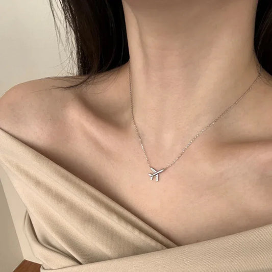 Silver-tone airplane CZ pendant necklace on neck with fine link chain.