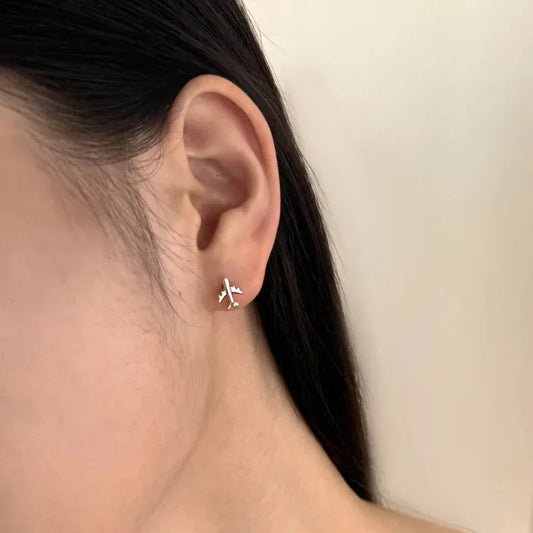 Silver airplane stud earrings on ear with butterfly backs
