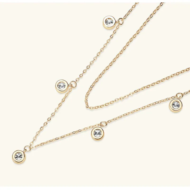 Layering necklace with gold chains and round moissanite disc charms, close view