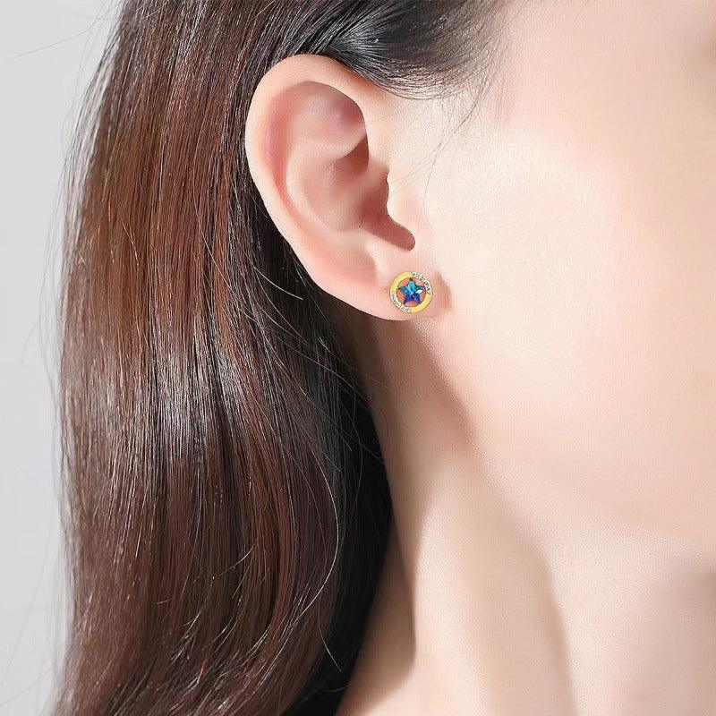 Gold star halo stud earring with blue center CZ on ear