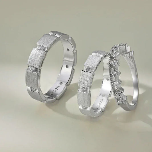 Silver-tone eternity band ring with frosted textured edges and small clear stones