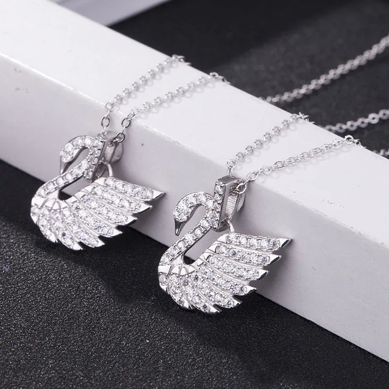 Swan pendant necklace with crystal pavé wing layers, silver-tone chain, angled close-up