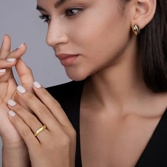 Gold moissanite wedding ring worn on a woman’s finger, star-set round stones