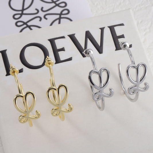 C-shaped stud earrings on display: gold-tone and silver-tone hoops with knot detail
