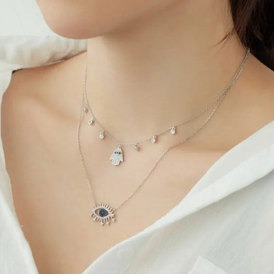 Silver tone necklace with small evil-eye pendant and dangling charm accents