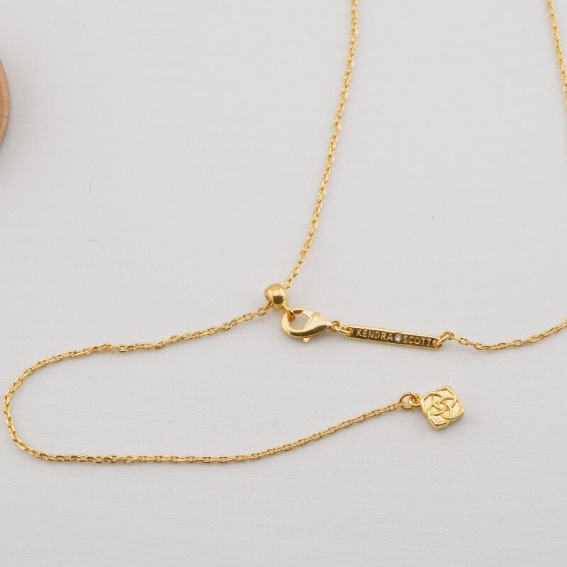 Gold-plated necklace with Kendra Scott logo clasp and dangling sports charm