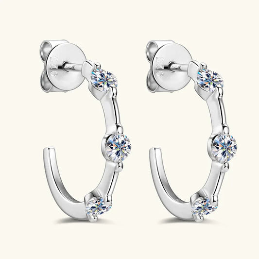 Silver three-stone C-hoop earrings with three round clear stones and hinged back.