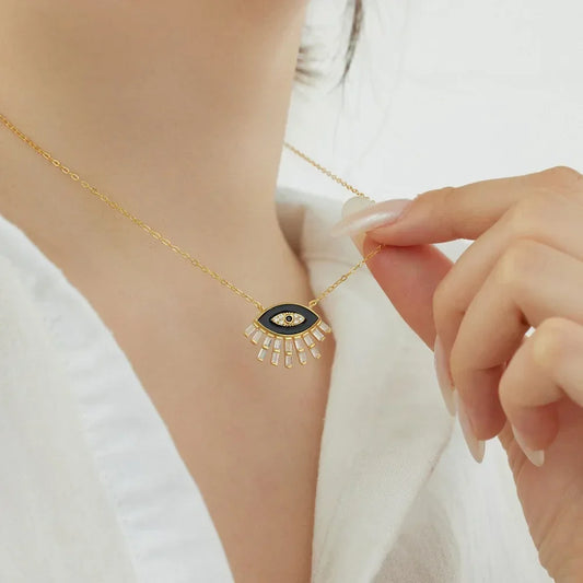 Gold-tone evil eye pendant necklace with black enamel center and crystal ray detail