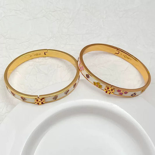 Gold-tone enamel bangle pair with flower and paw charm details
