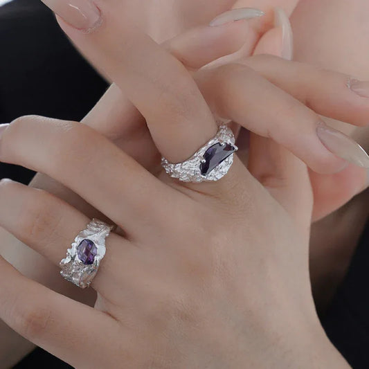Silver irregular-texture ring with purple center stone, worn on fingers