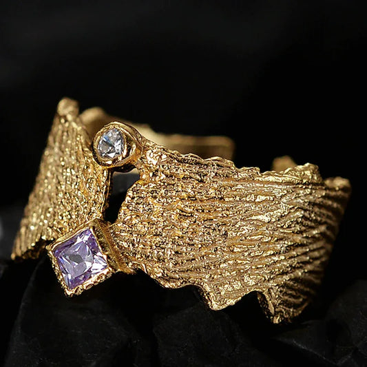 Textured open band ring in gold tone with square purple gem and round clear stone