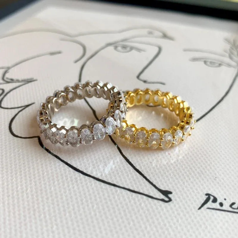 Pair of oval CZ love rings on display: silver-tone and gold-tone pavé