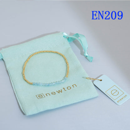 Elastic beaded bracelet with gold round beads and aqua blue bead accent row.