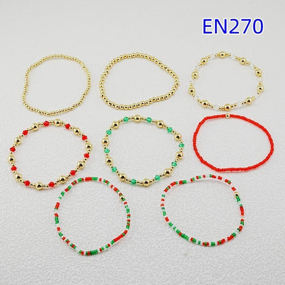 Eight beaded bracelets in gold-tone, red, and green with elastic cords, laid out